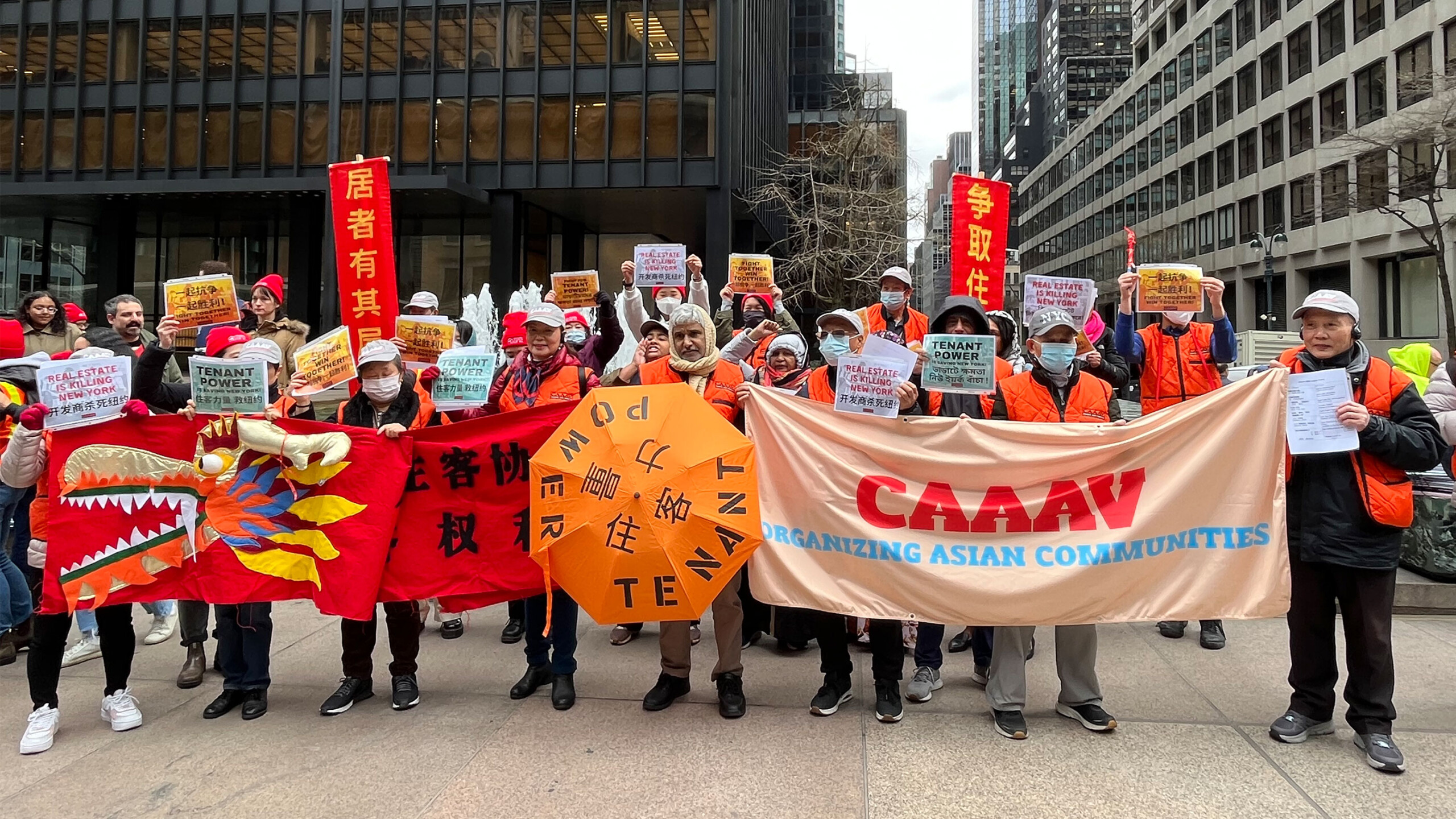 Group holding banners and signs at an Asian community organizing event.