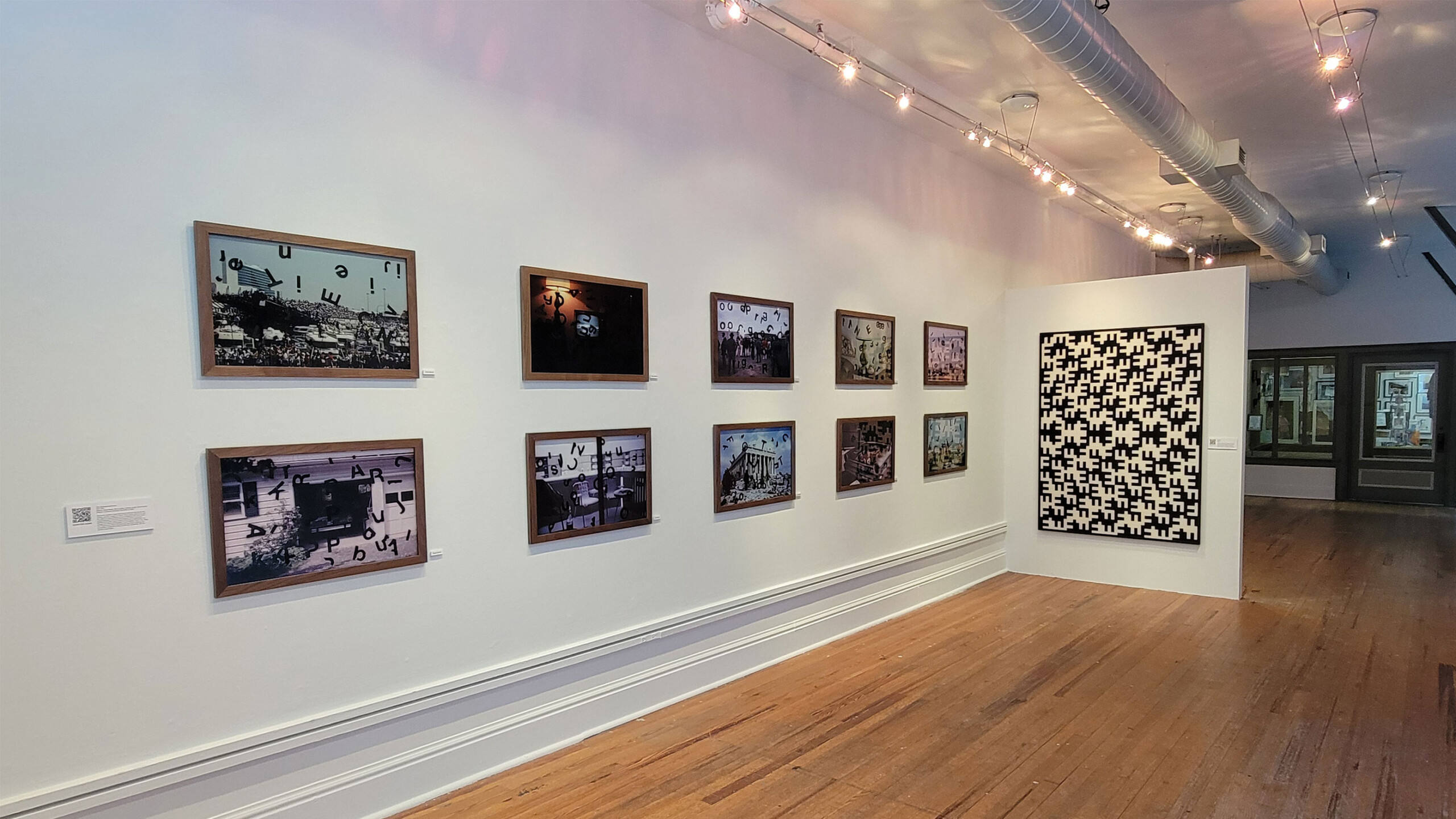 Art gallery interior with various framed photos on walls and a patterned artwork on right.