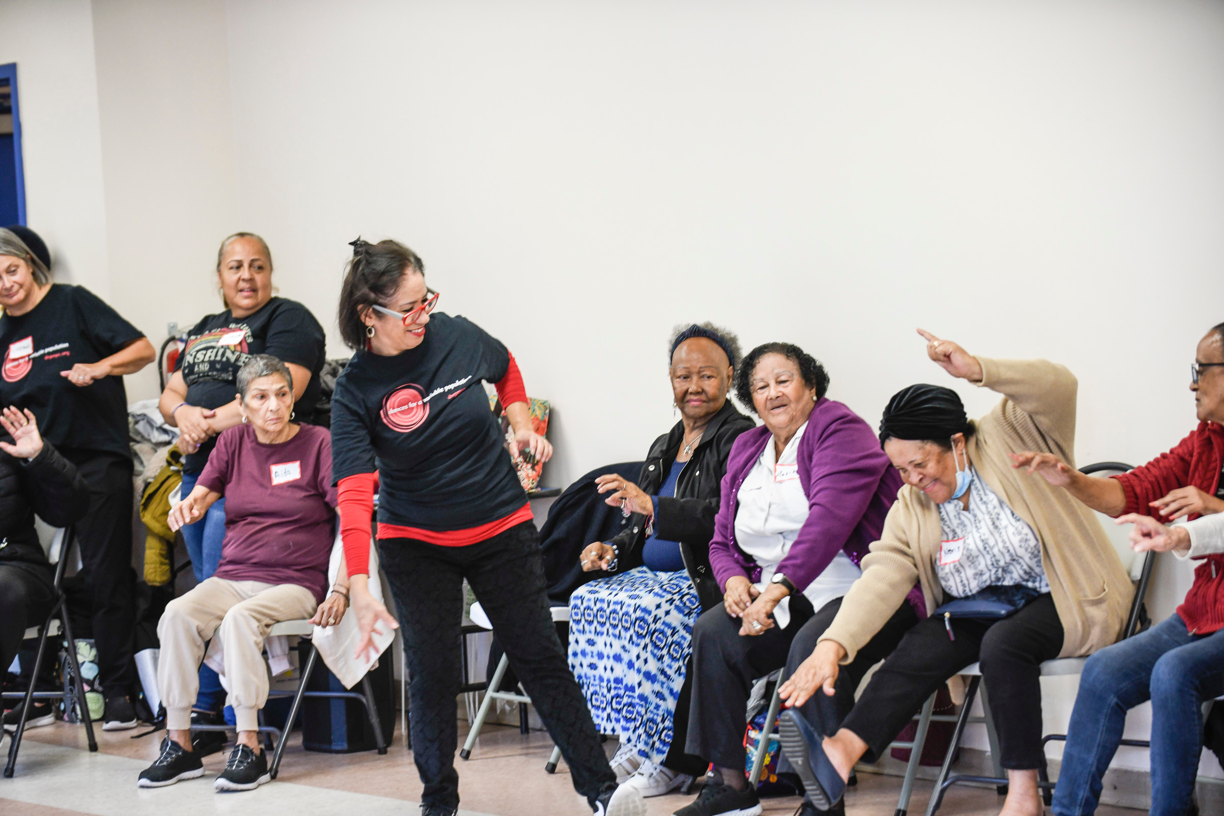 Group of people in a workshop sitting and gesturing with hands raised.