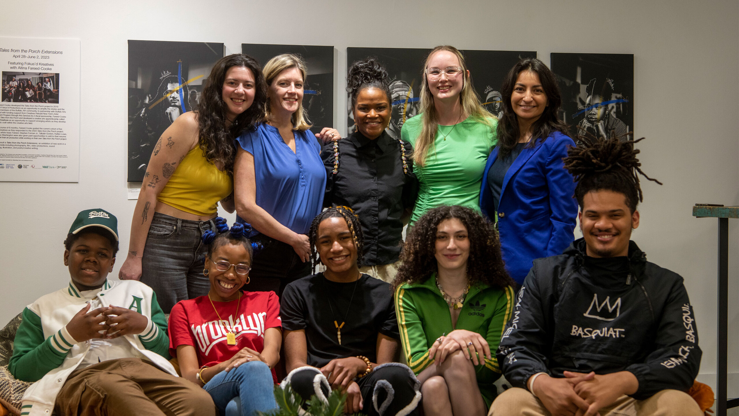 Group of people posing together indoors, dressed in casual and smart attire.
