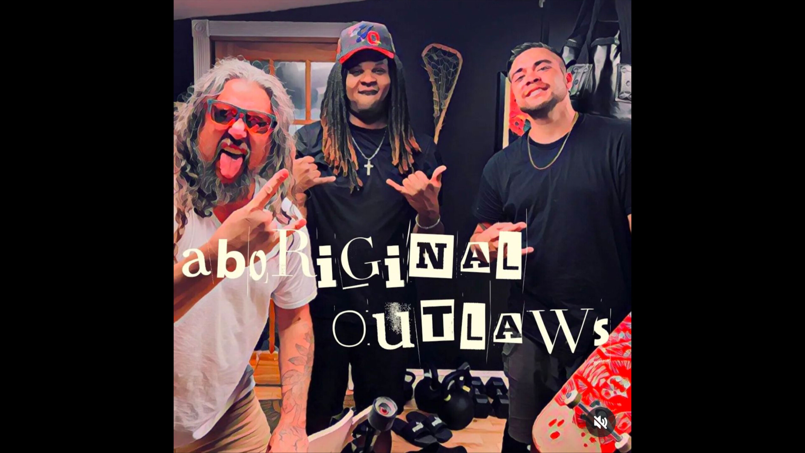 Three people are standing together and posing for the camera in what appears to be a casual indoor setting. In the foreground, a man with long, wavy hair is making...