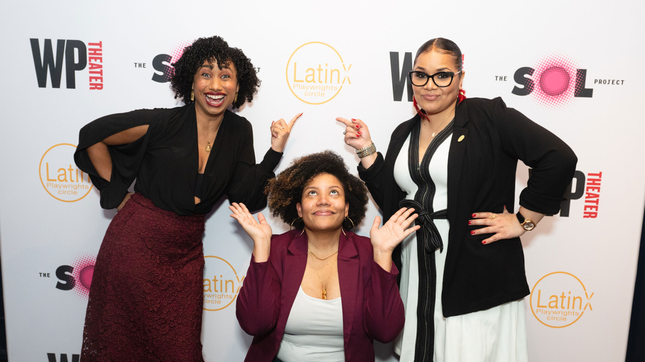 Four people posing together at an event with a branded backdrop.