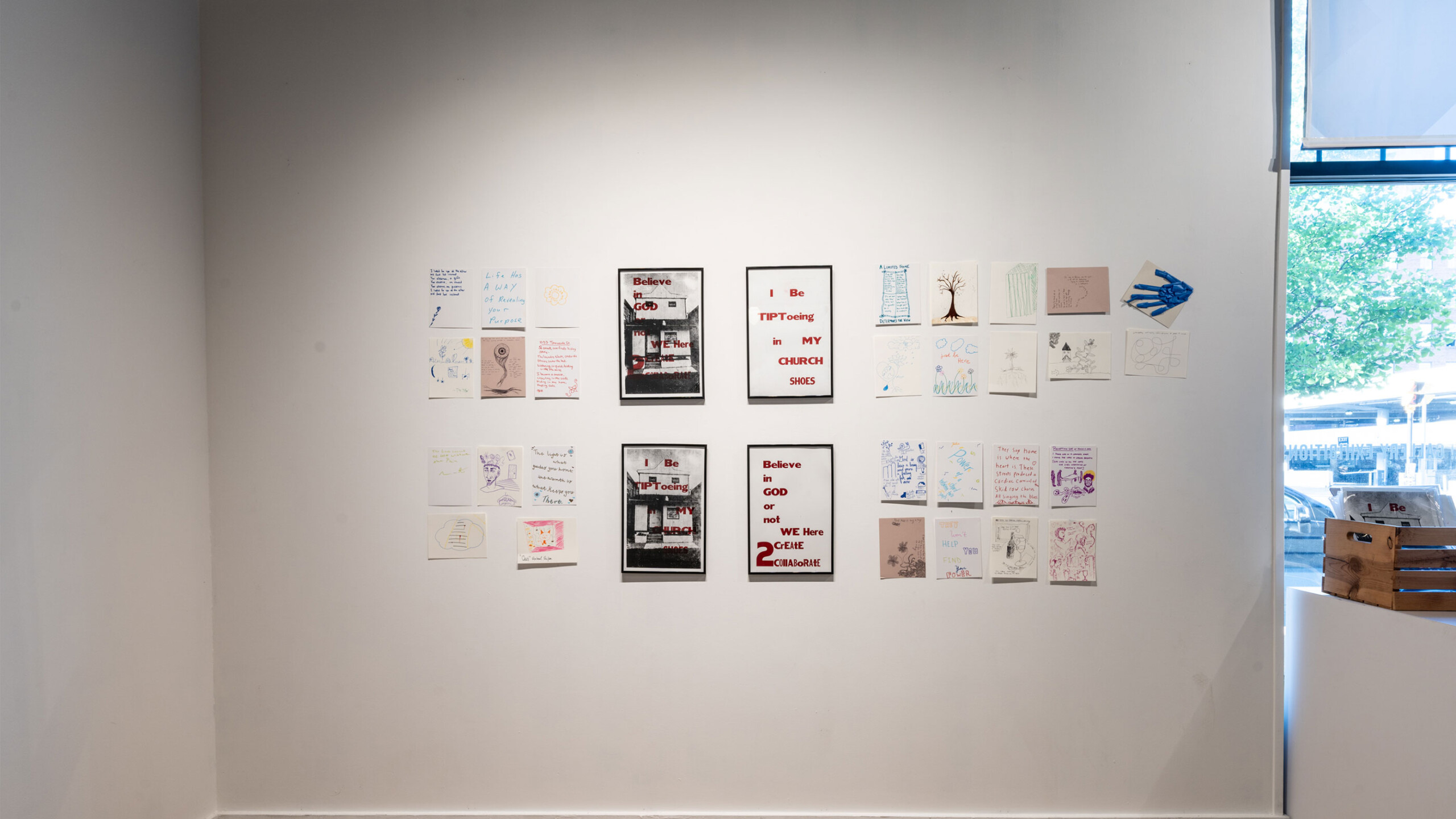 A minimalist art gallery wall featuring a collection of artwork pieces arranged in a grid pattern. The display includes a mix of colorful and monochrome sketches,...