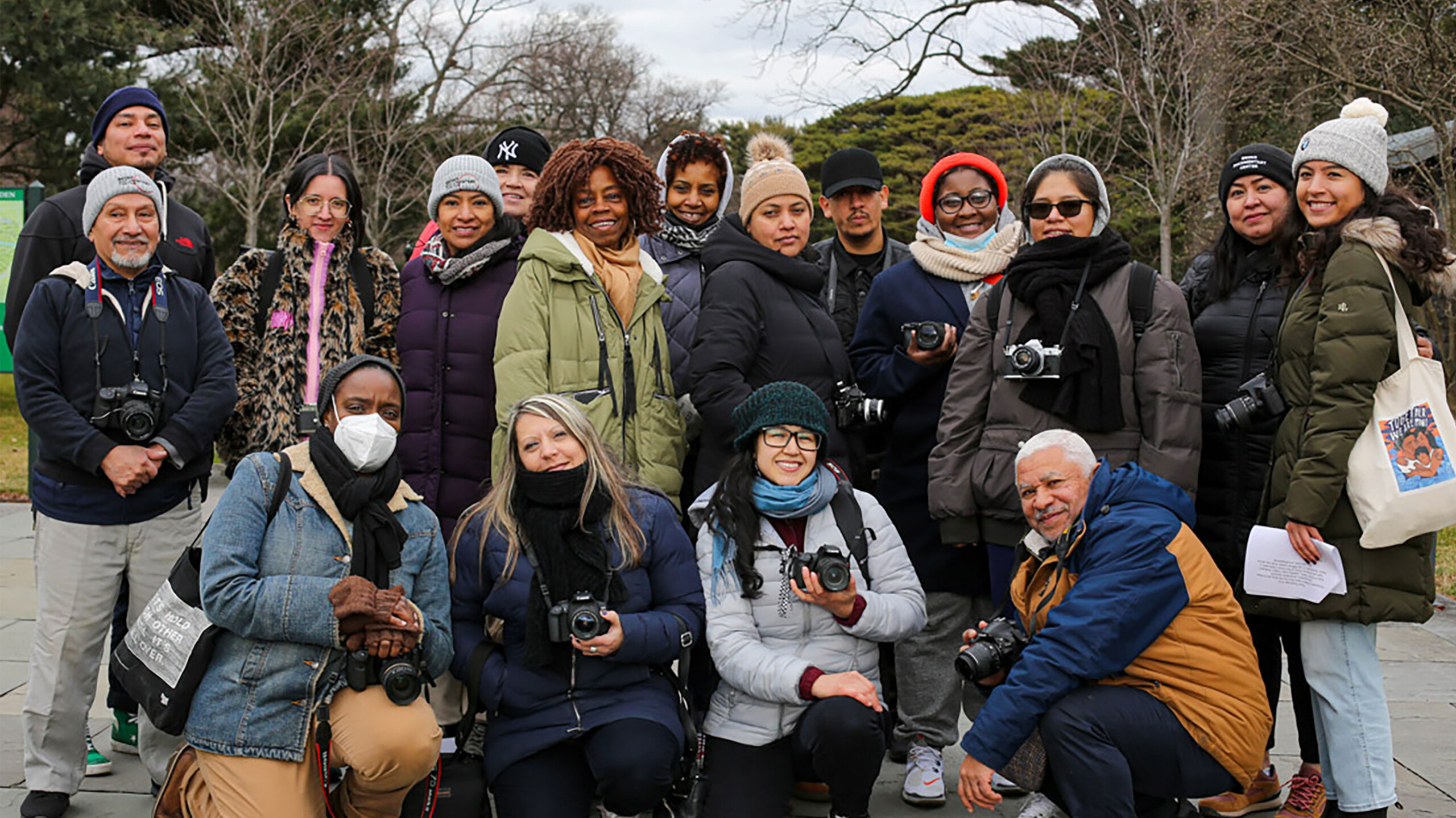 Group of people with cameras, possibly on a photography outing, standing outdoors.