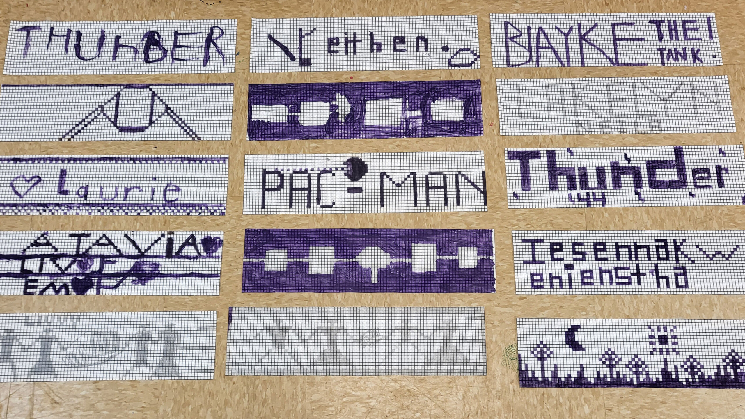 A collection of rectangular grid papers, each adorned with unique, hand-drawn designs and text in black and purple ink. The designs feature a variety of themes:...