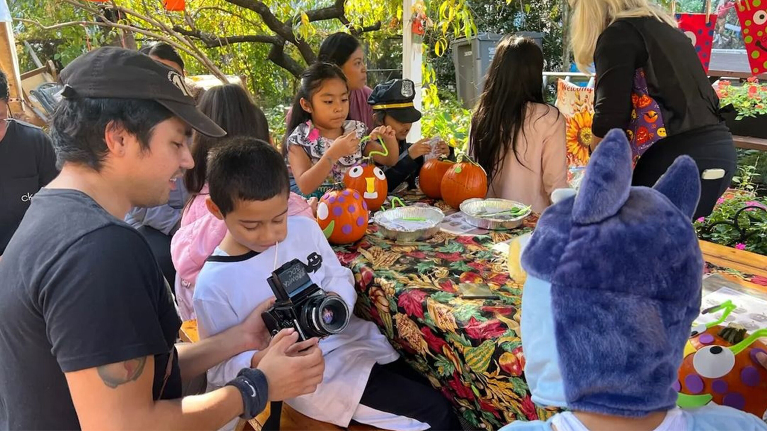 People engaging in pumpkin painting at an outdoor table.