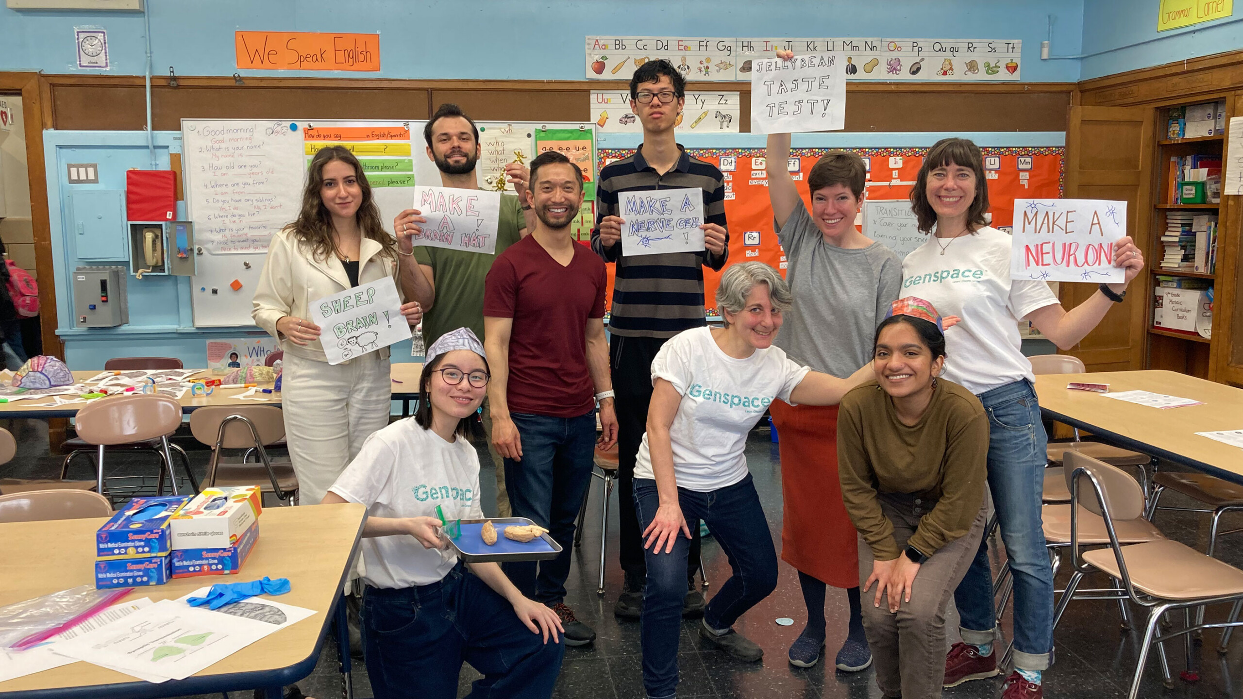 Group of students holding science-related signs in a classroom.