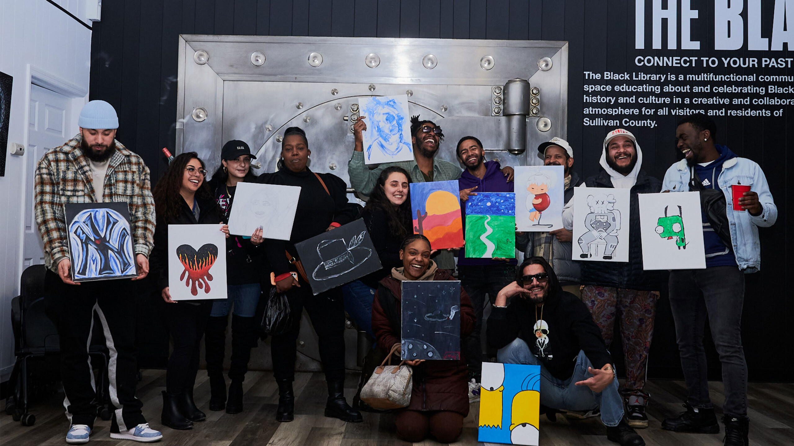 A person walks along a sidewalk in front of a brick building with large windows. The entrance is marked by a sign that reads 'The Black Library' above the door....