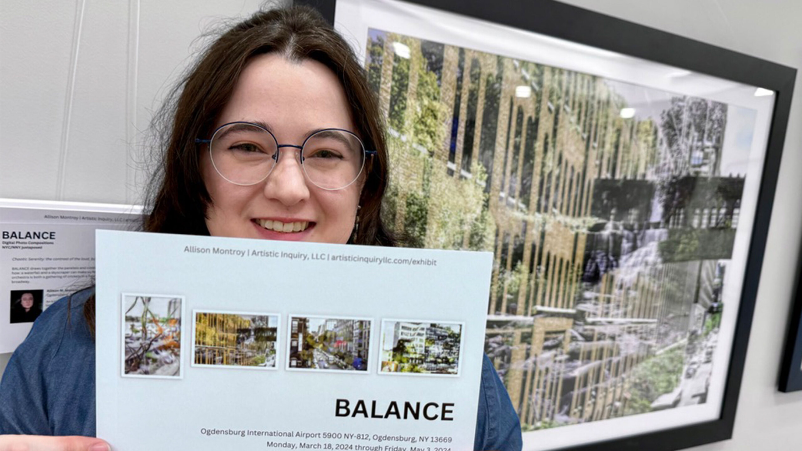 A person with long hair and glasses smiles while holding a printed sheet featuring images of an artwork titled 'BALANCE'. The artwork, showcased in an exhibition...