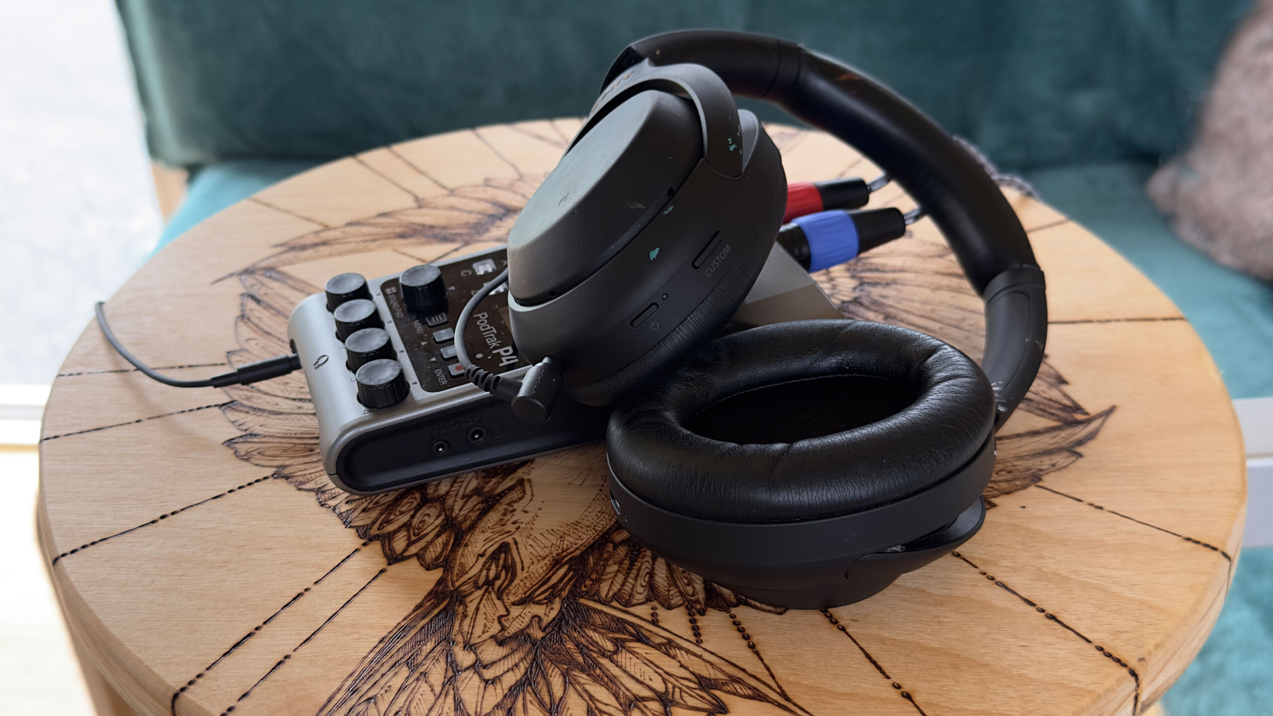 A spacious, brightly lit yoga studio is arranged for a session. Yoga mats are laid out on the wooden floor, each accompanied by dark blue bolsters, colorful woven...