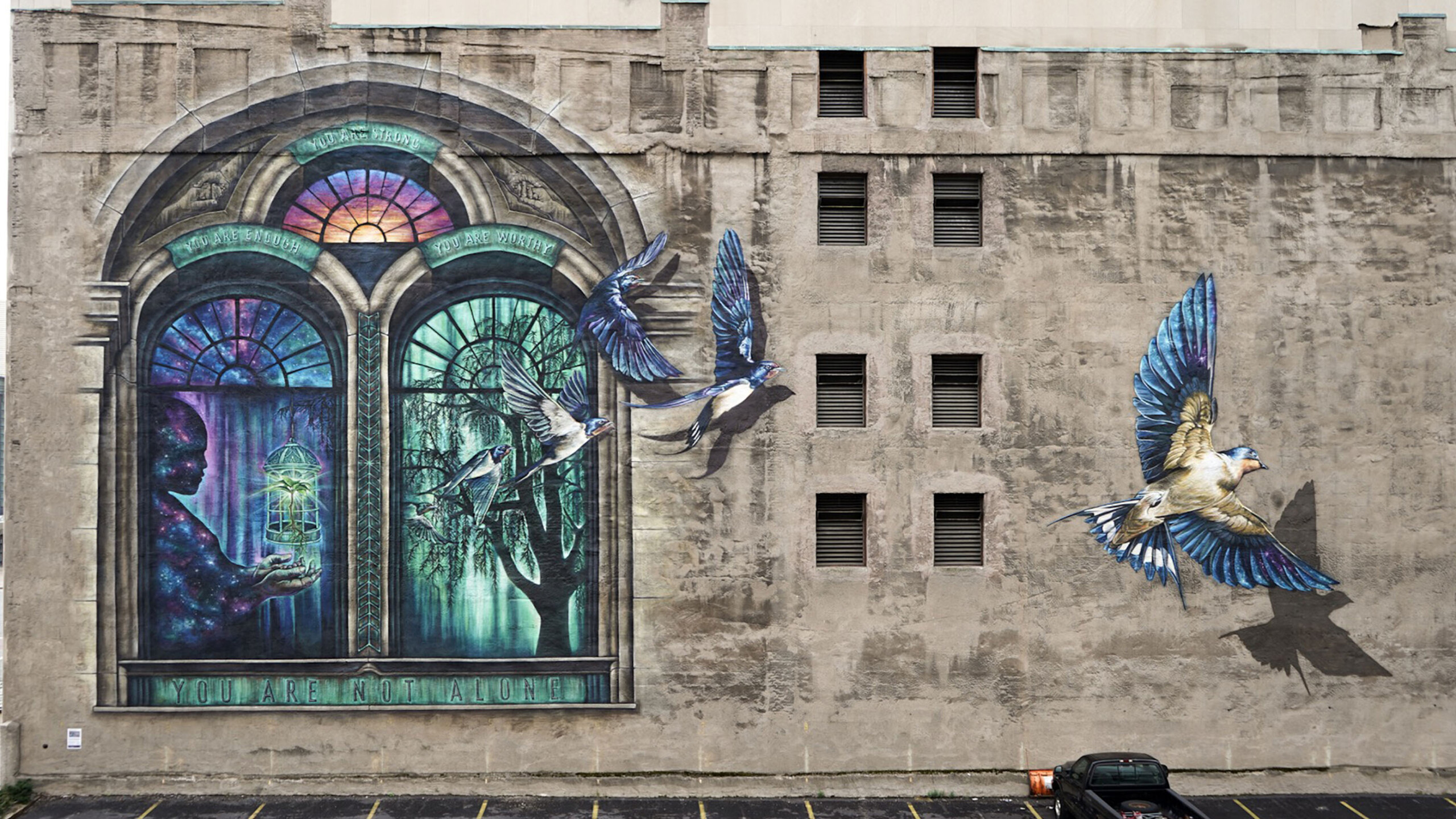 The image features a building adorned with stained glass windows, showcasing artistic designs. It includes elements of the outdoors, with the building situated...